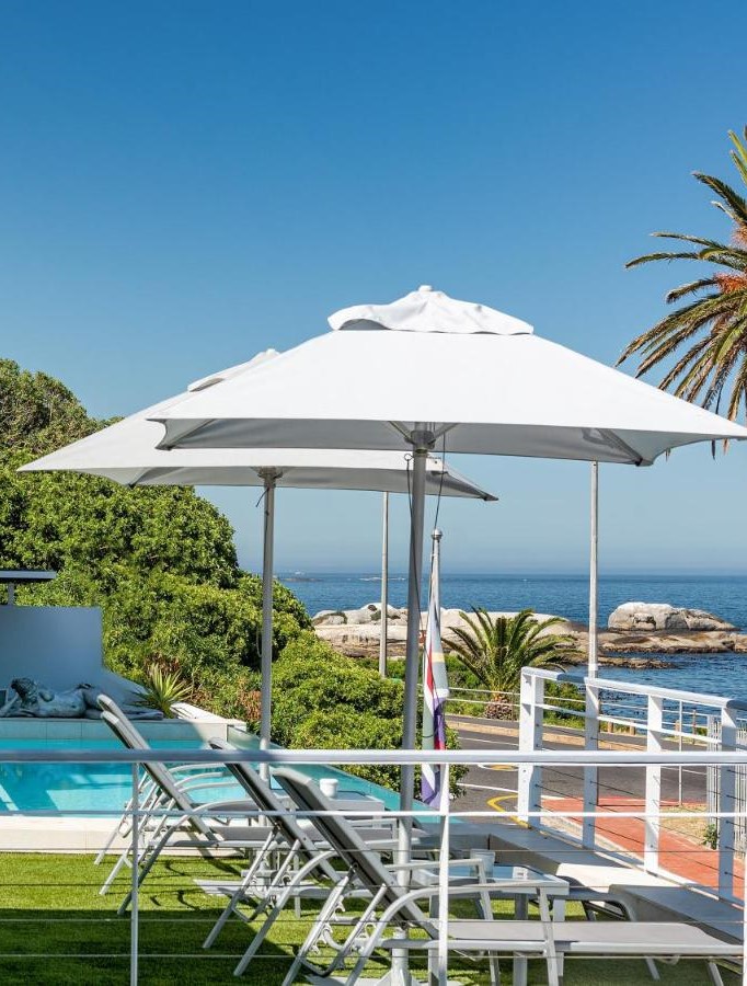 South Beach Camps Bay, Kaapstad. Ligstoelen en parasols aan het zwembad, met uitzicht op zee.