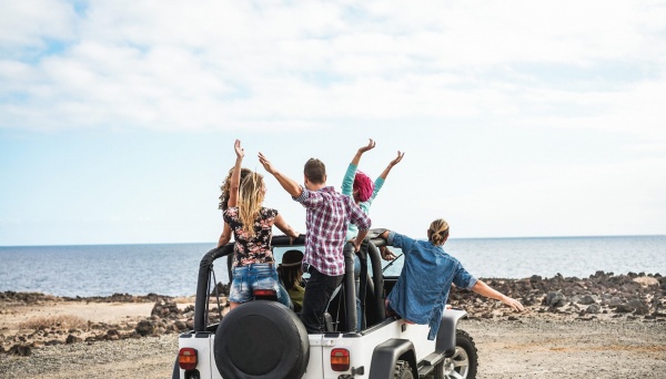 Group of friends doing excursion around desert with convertible 4x4 car - Friendship, tour, youth, lifestyle and vacation concept - Focus on guys bodies